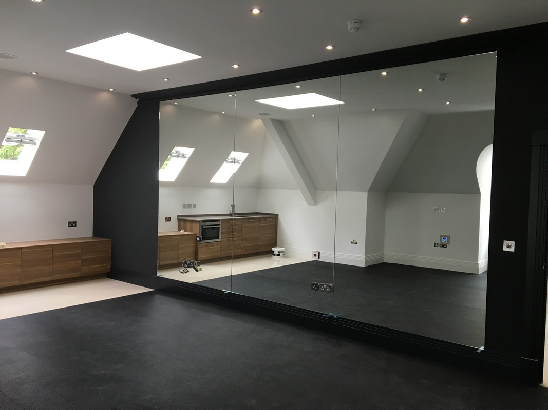 Frameless glass wall dividing loft conversion in Caterham